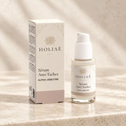 Sérum Anti-Taches à l’Alpha-Arbutine HOLIAĒ avec flacon et étui sur fond ivoire
