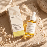 Huile Visage Hydratante & Sublimatrice HOLIAĒ en mise en scène éditoriale sur travertin