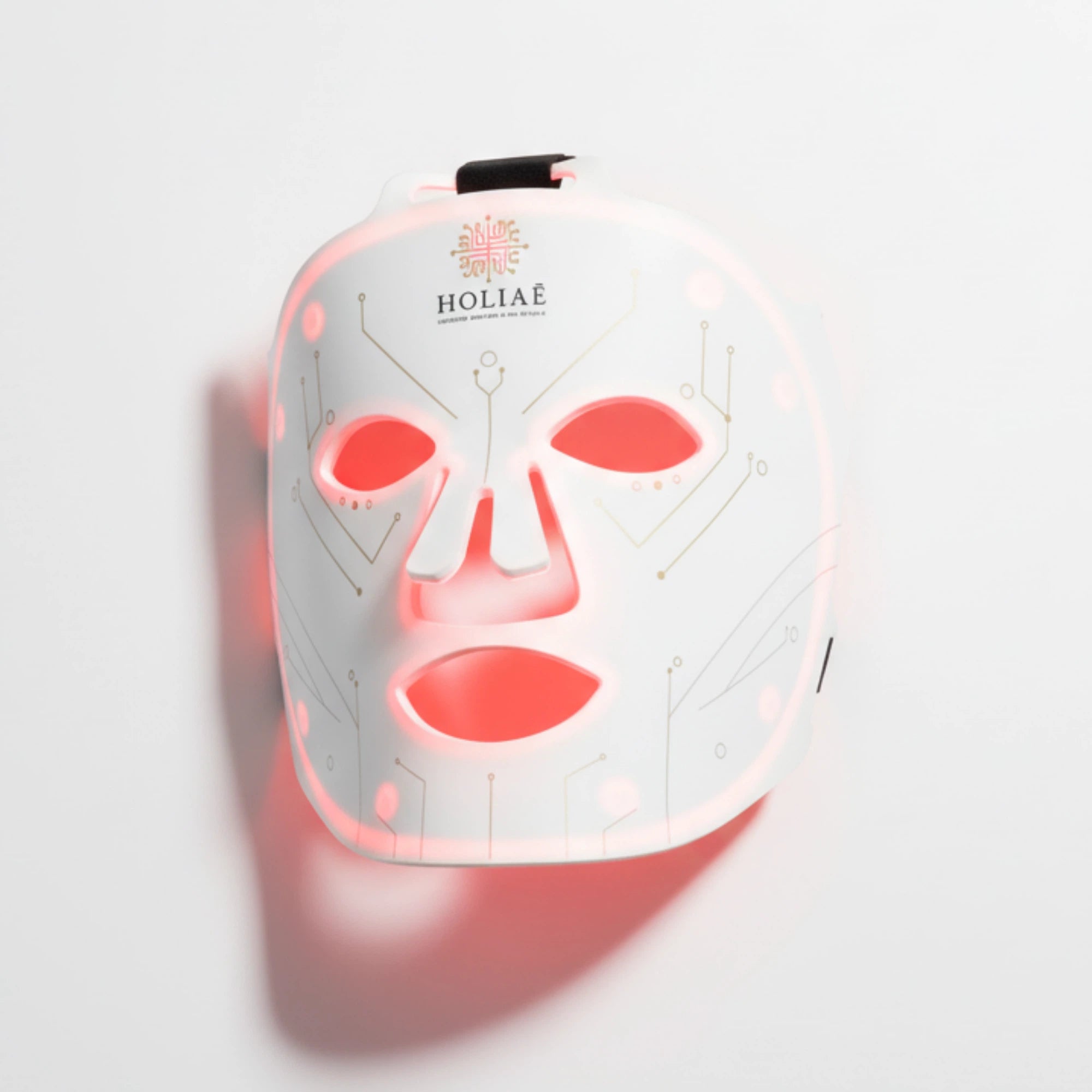 Masque LED Holiaē RĒ:GEN I allumé en lumière rouge, vu de face sur fond blanc minimaliste.