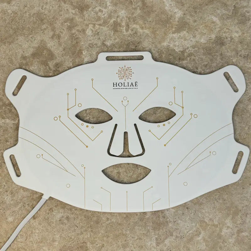 Masque LED visage Holiaē RĒ:GEN I — face externe blanche avec circuits dorés, vue à plat.