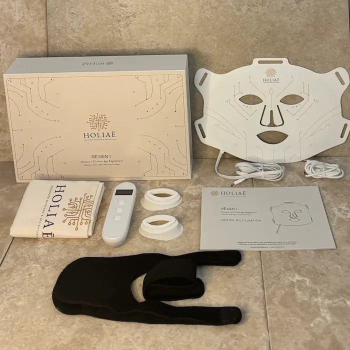Coffret Holiaē RĒ:GEN I — masque LED visage, télécommande, sangles, coussinets et notice.