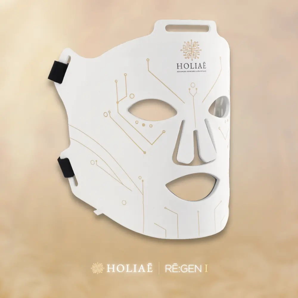 Masque LED Holiaē RĒ:GEN I sur fond champagne, technologie spa-tech de luxe alliant science et esthétique pour une peau régénérée.