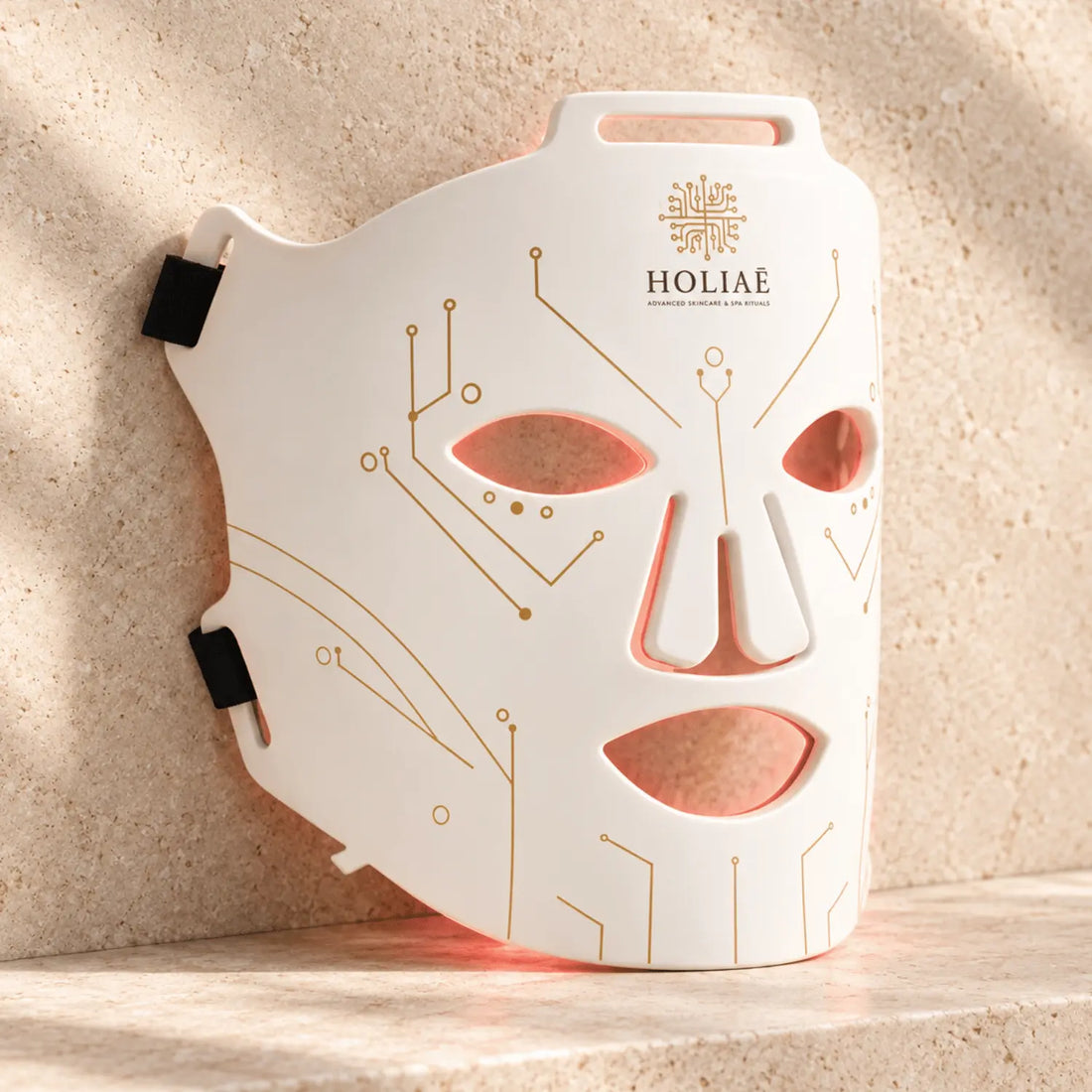 Masque LED visage anti-âge RĒ:GEN I HOLIAĒ, vue produit sur fond travertin ivoire