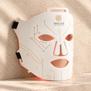 Masque LED visage anti-âge RĒ:GEN I HOLIAĒ, vue produit sur fond travertin ivoire