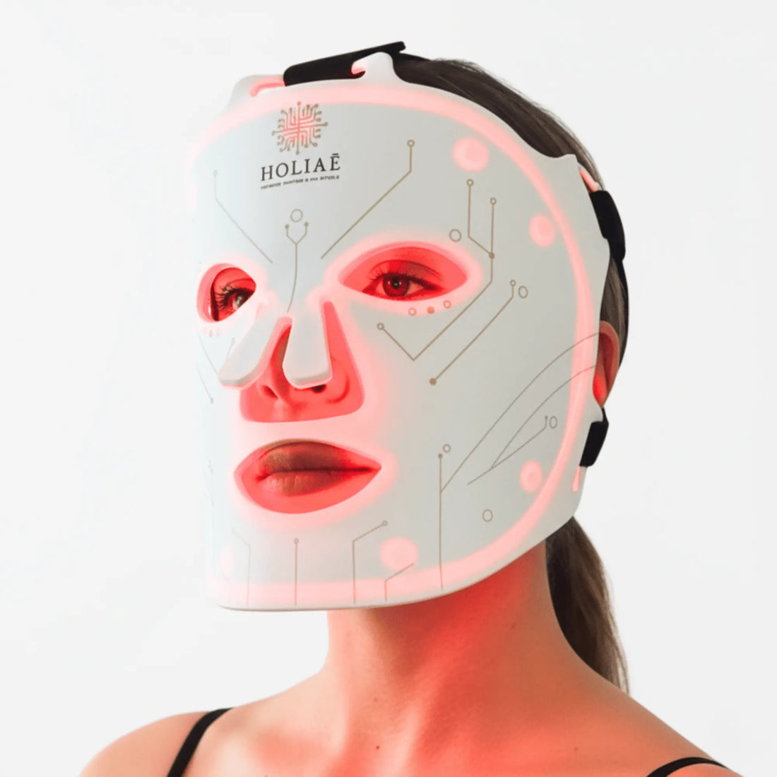 Femme utilisant le masque LED Holiaē RĒ:GEN I en lumière rouge 660 nm, soin anti-âge professionnel pour stimuler le collagène et régénérer la peau.