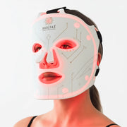 Femme utilisant le masque LED Holiaē RĒ:GEN I en lumière rouge 660 nm, soin anti-âge professionnel pour stimuler le collagène et régénérer la peau.