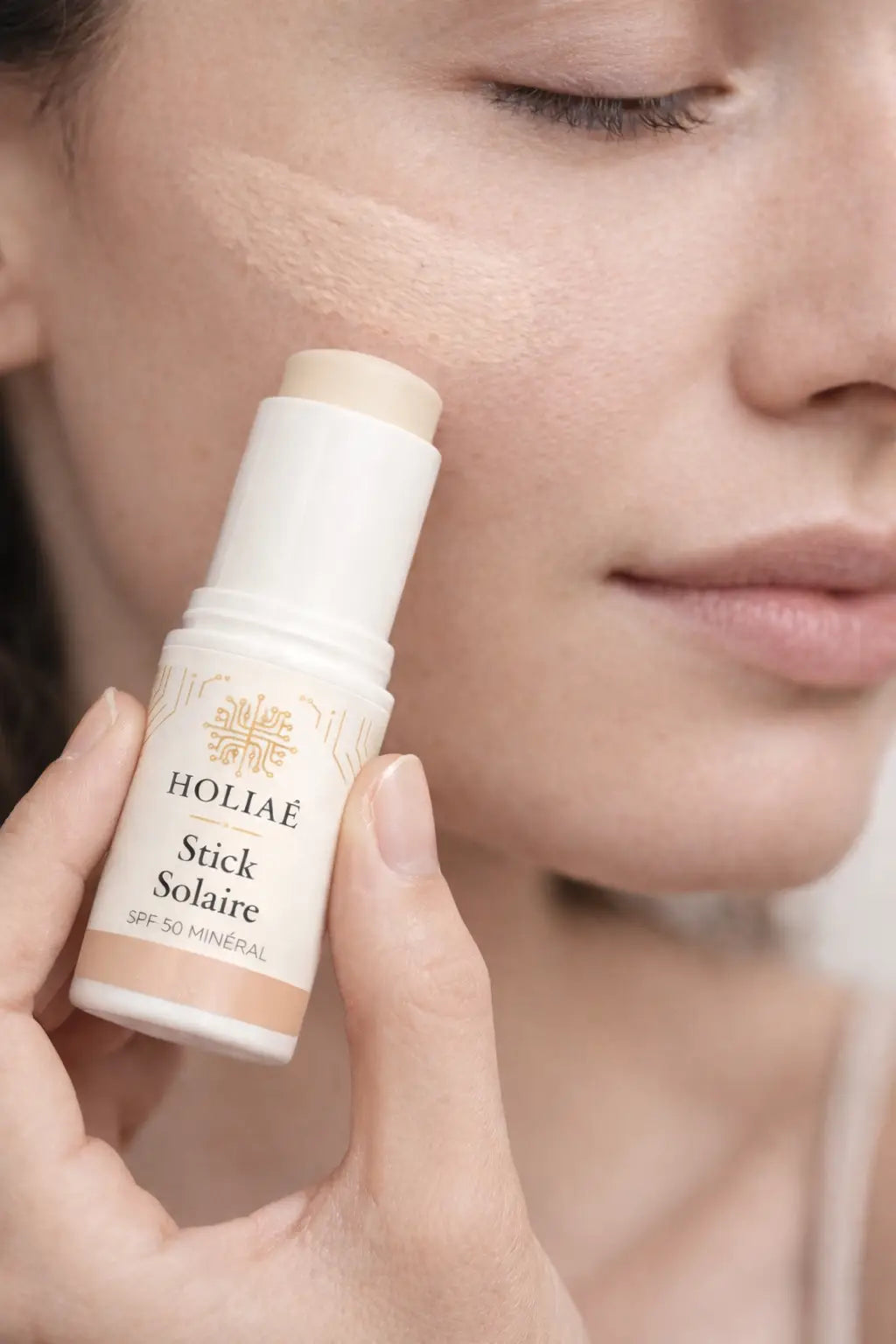 Application du stick solaire minéral SPF50 sur le visage pour protection UV quotidienne